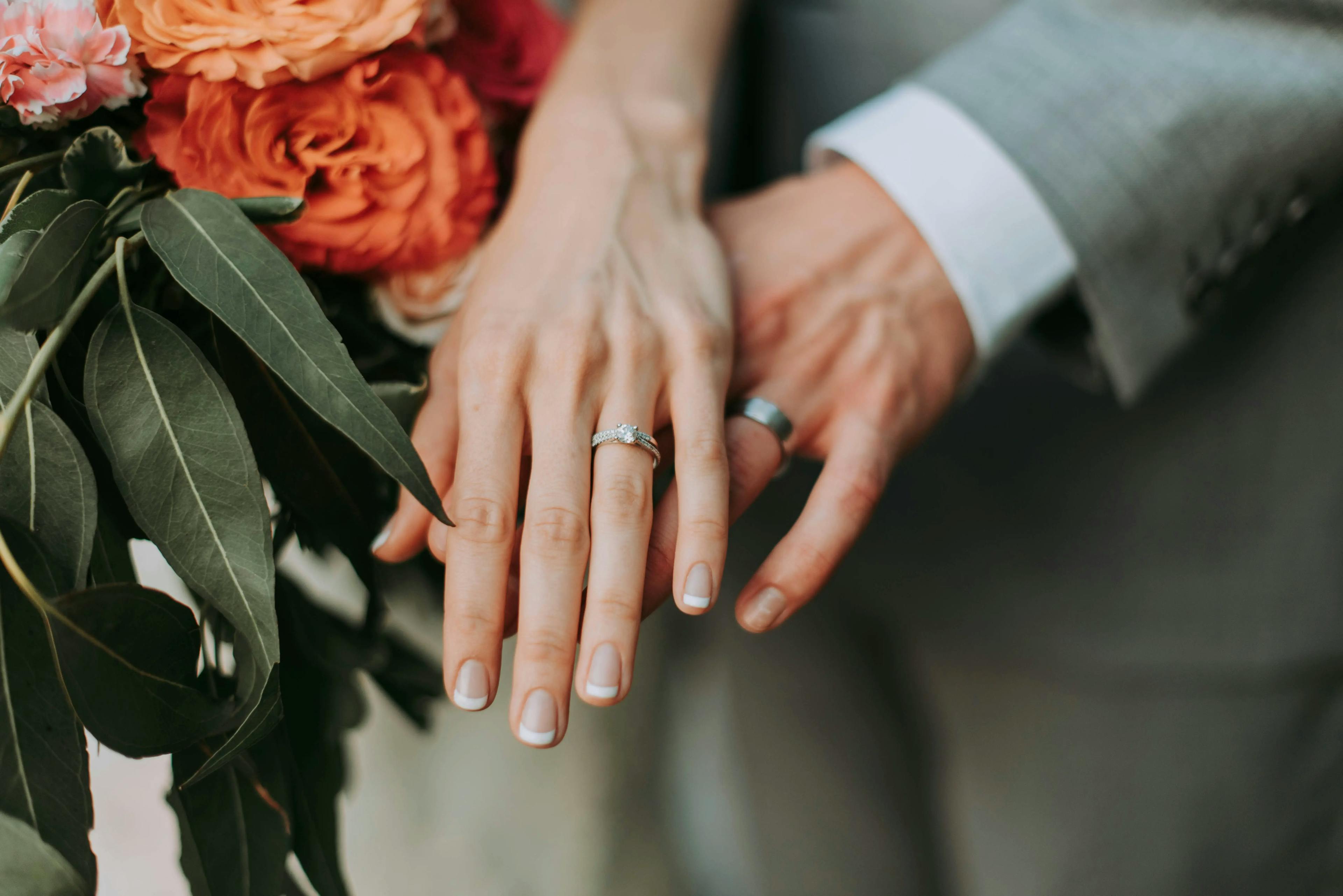 A close-up of the hands of a bride and groom, symbolizing their union and commitment on their wedding day.
