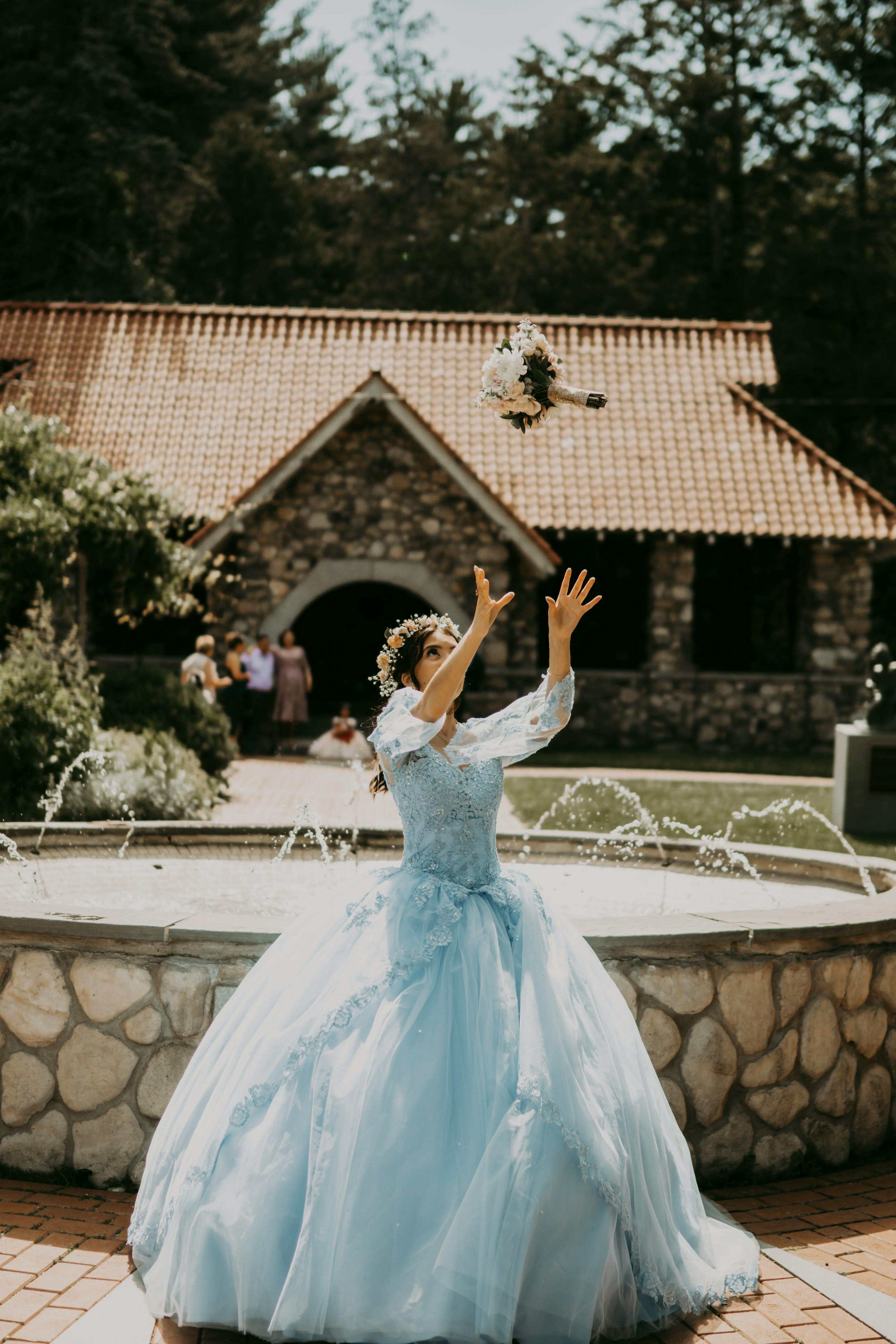 A person in elegant blue dress throwing bouquet at celebration.