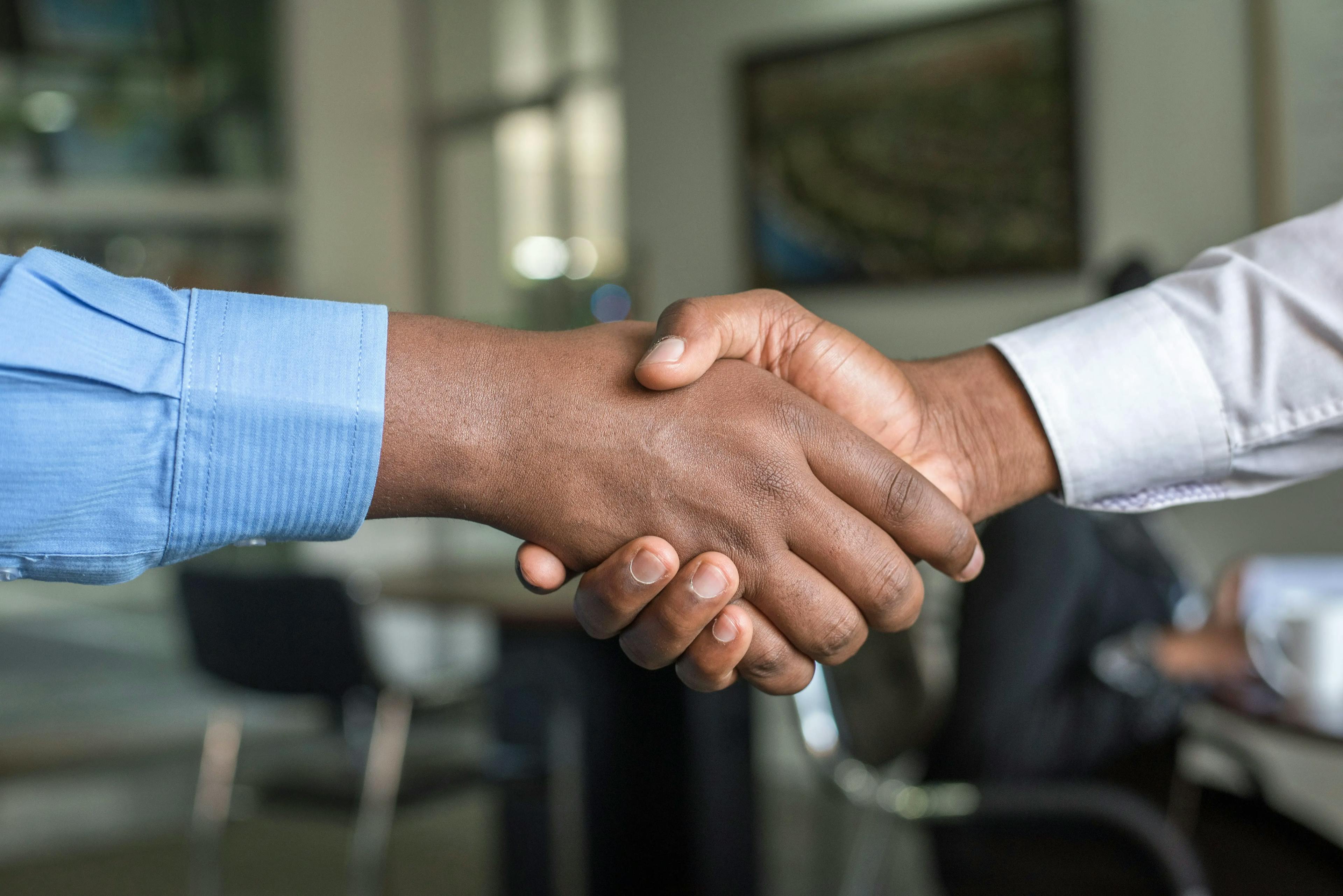 Two professionals shaking hands in a modern office setting, symbolizing a successful business deal.