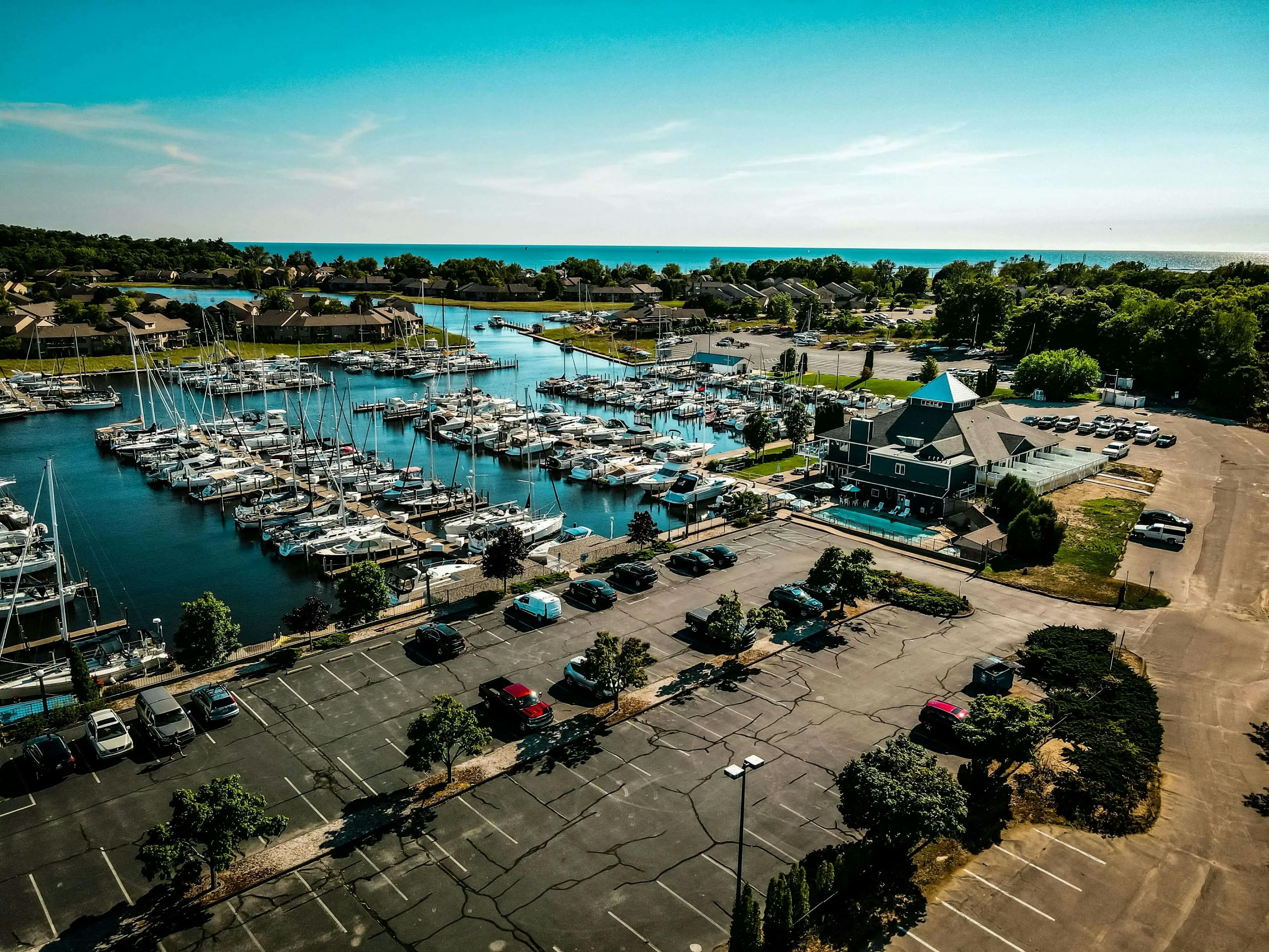 Aerial view of a marina with boats parked and a parking lot.
